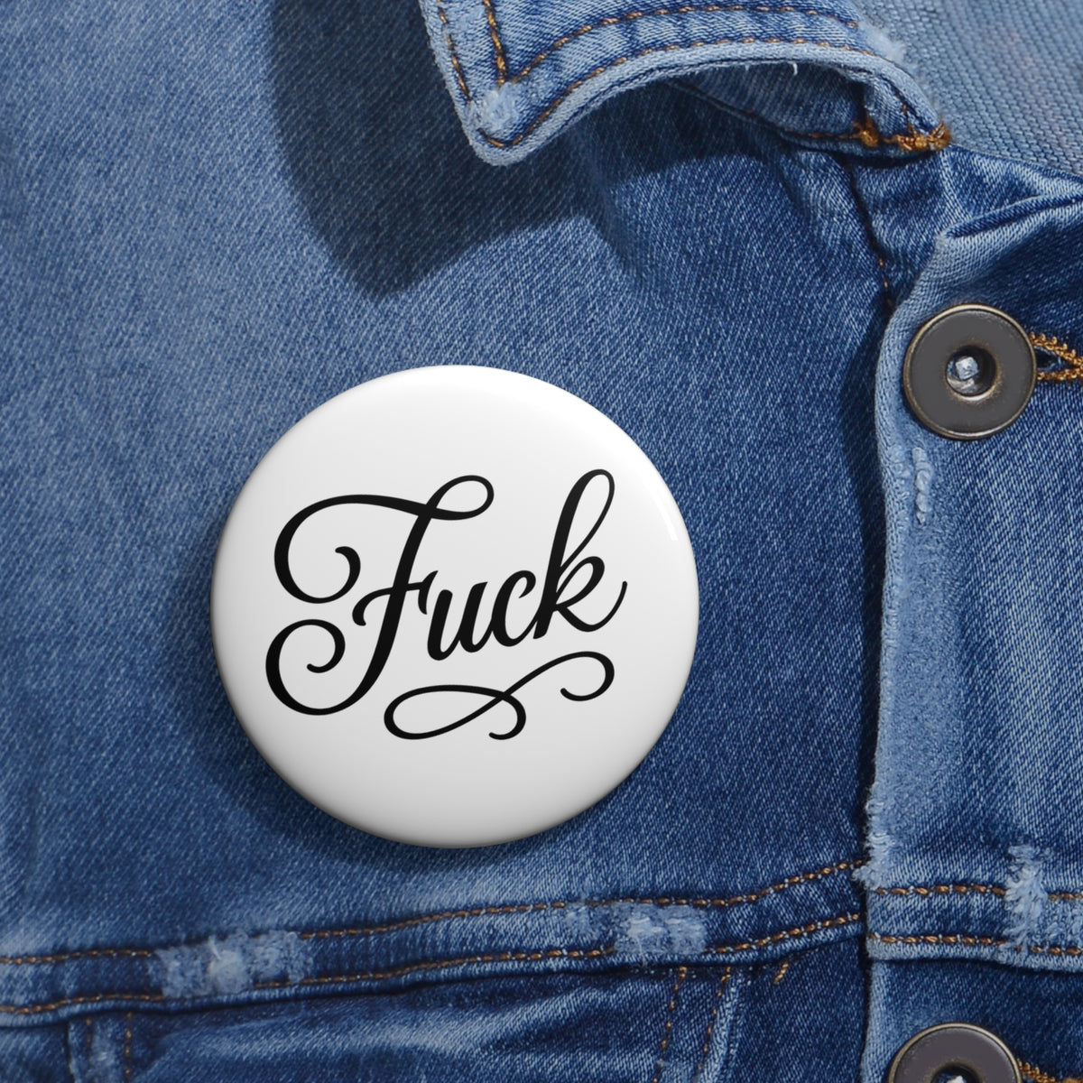 Round white pin button with black script FUCK lettering and steel pin back
