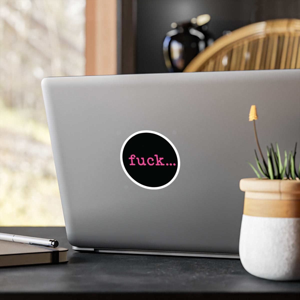 Round black vinyl sticker with lowercase motel-pink fuck and an ellipsis