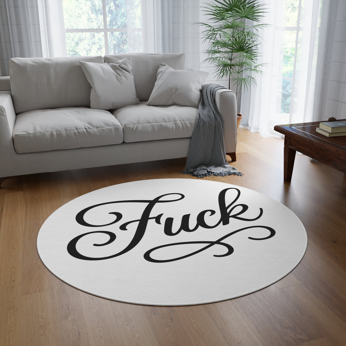 White round chenille rug printed with large black script FUCK lettering