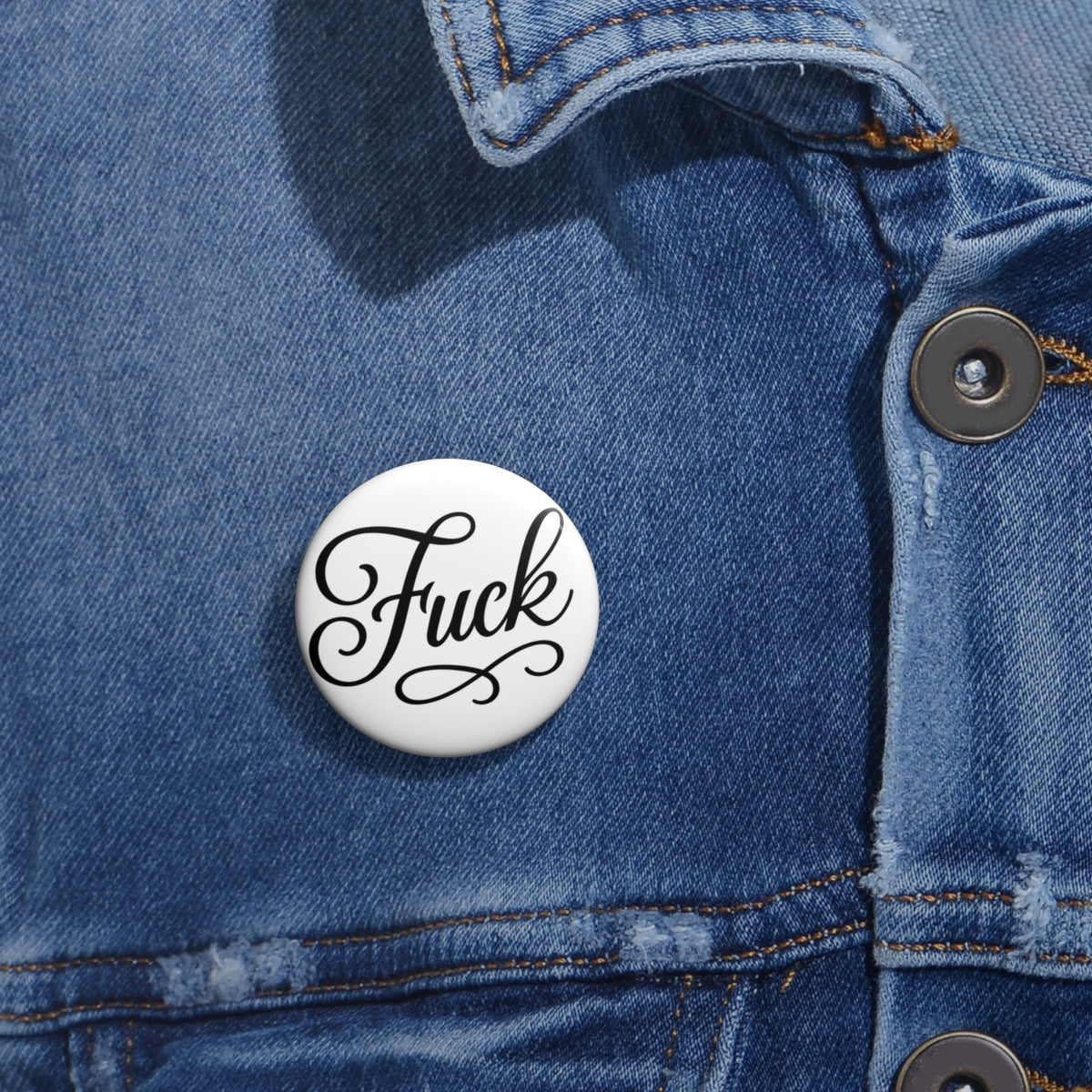Round white pin button with black script FUCK lettering and steel pin back