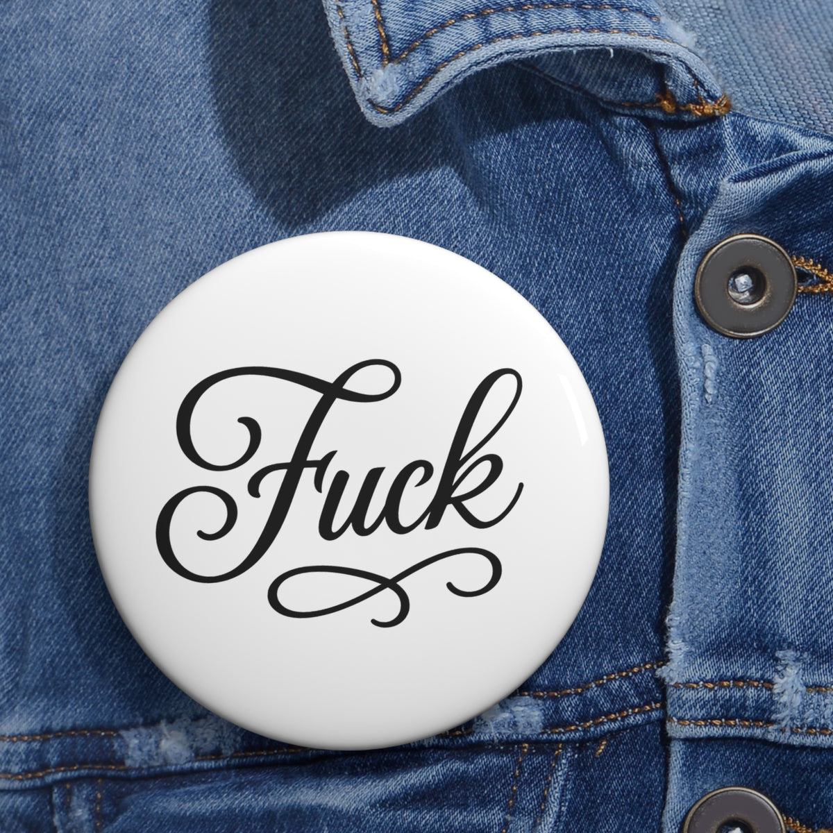 Round white pin button with black script FUCK lettering and steel pin back